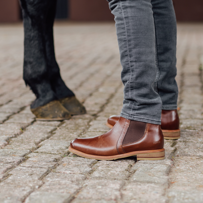 Men wearing   boots in front of a horse